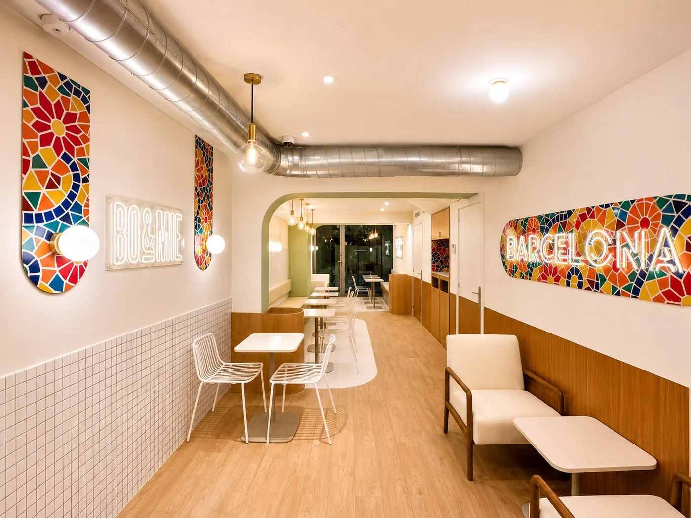 La salle de BO&MIE Barcelona : mosaïques de céramique colorée, enseignes au néon BO&MIE et Barcelona, tables claires et parquet de chêne