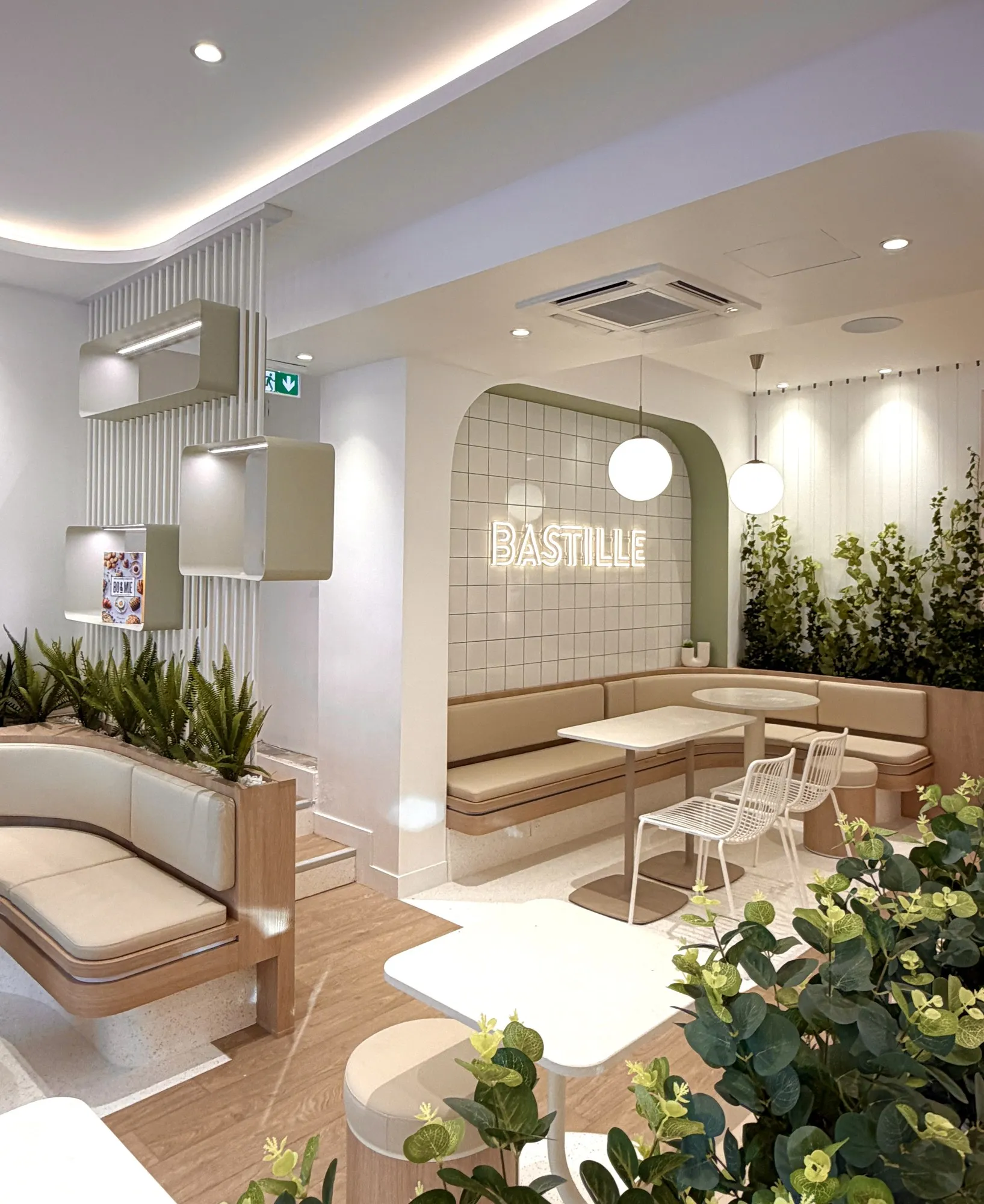 La salle de la boutique BO&MIE Bastille : enseigne au néon, banquettes en alcôve et murs végétalisés