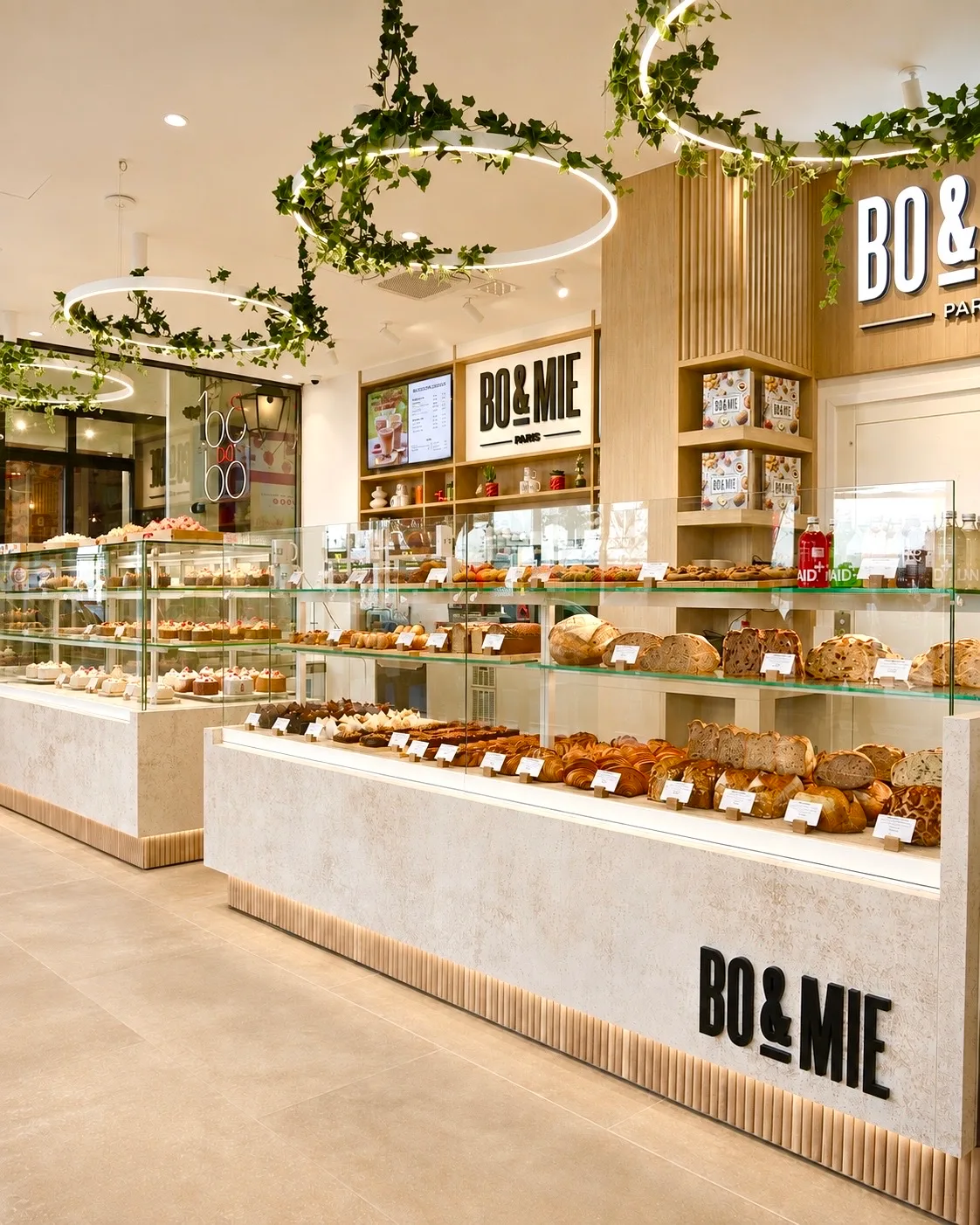 BO&MIE Montmartre : anneaux lumineux piqués de lierre au-dessus des comptoirs de pains et de pâtisseries