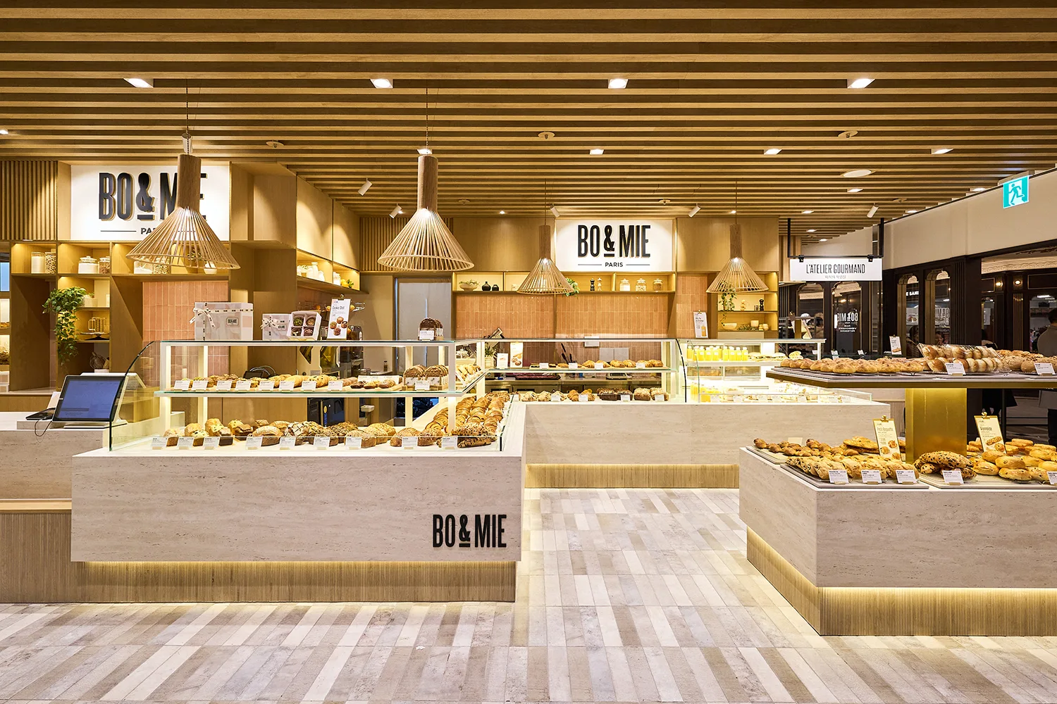 BO&MIE Séoul : plafond à lattes de bois, suspensions et comptoirs de travertin garnis de pains et viennoiseries