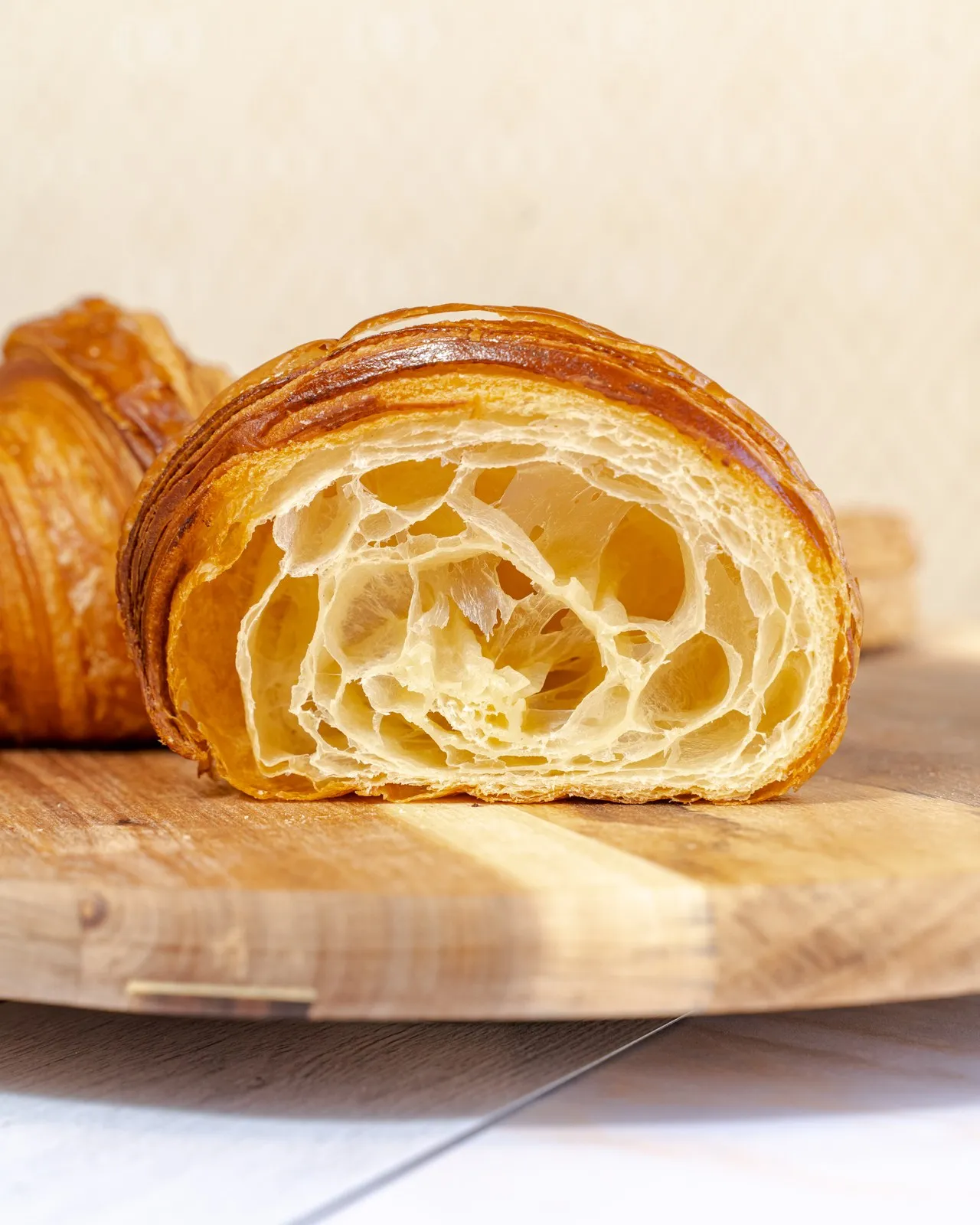 Un croissant BO&MIE coupé en deux sur une planche de bois : le feuilletage alvéolé et la croûte dorée en gros plan