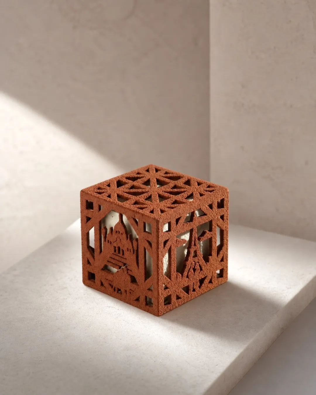 Amour³, cube de chocolat ajouré BO&MIE aux motifs de la tour Eiffel, du pont des Arts, du Moulin Rouge et de Montmartre, posé sur une pierre claire en lumière rasante