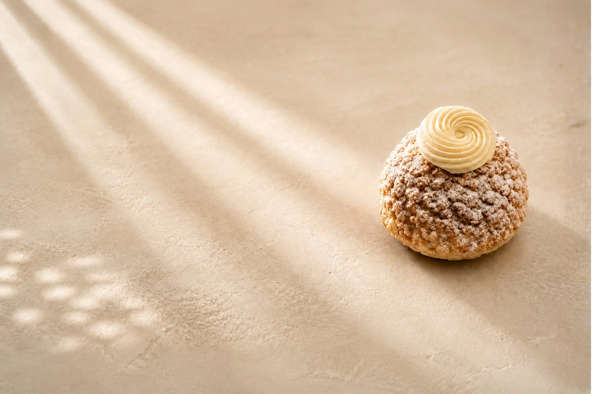 Un chou craquelin BO&MIE poudré de sucre glace, couronné d’une rosace de crème vanille