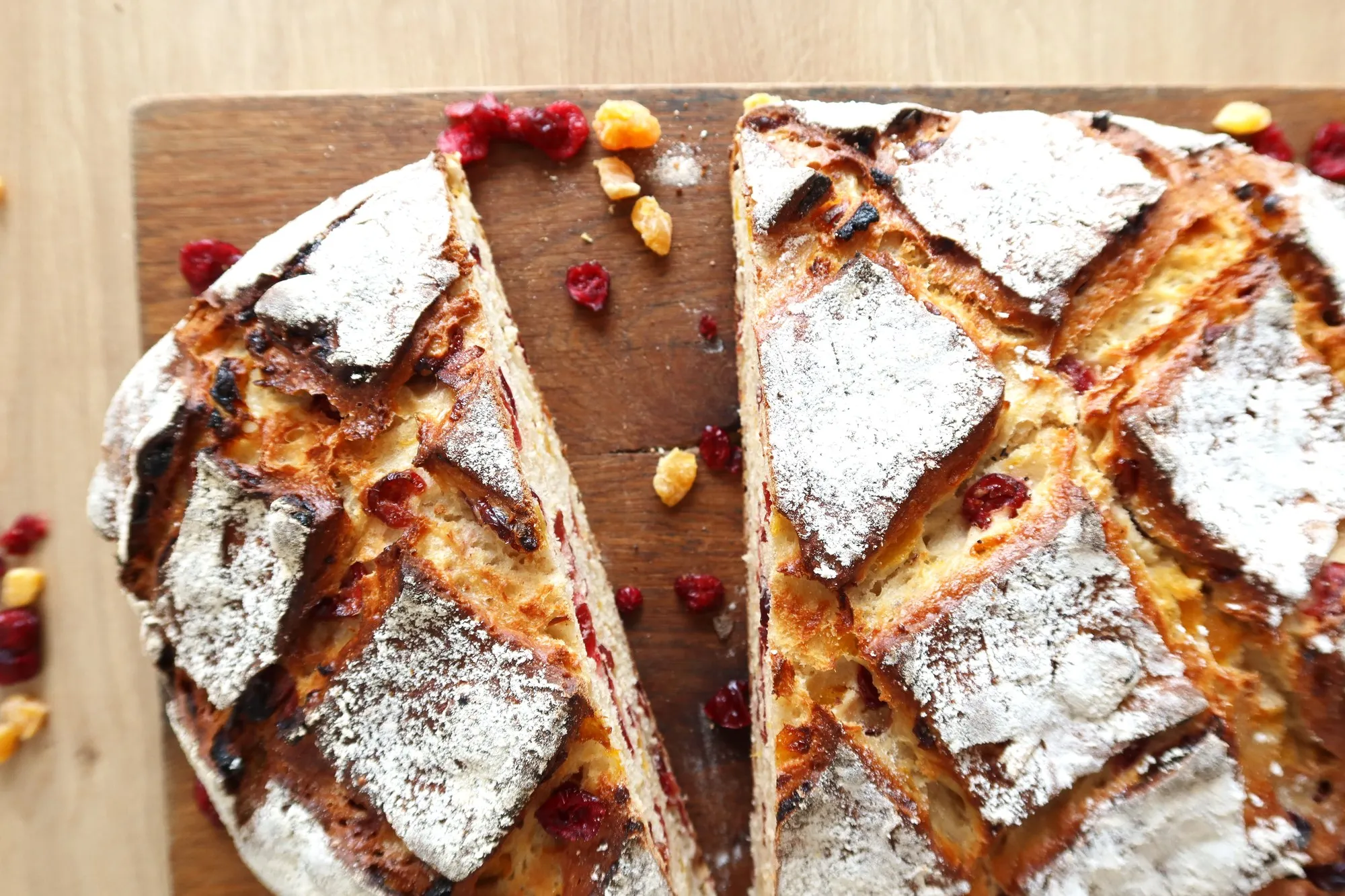 Un pain BO&MIE aux abricots et aux cranberries, coupé en deux sur une planche, croûte farinée et scarifiée