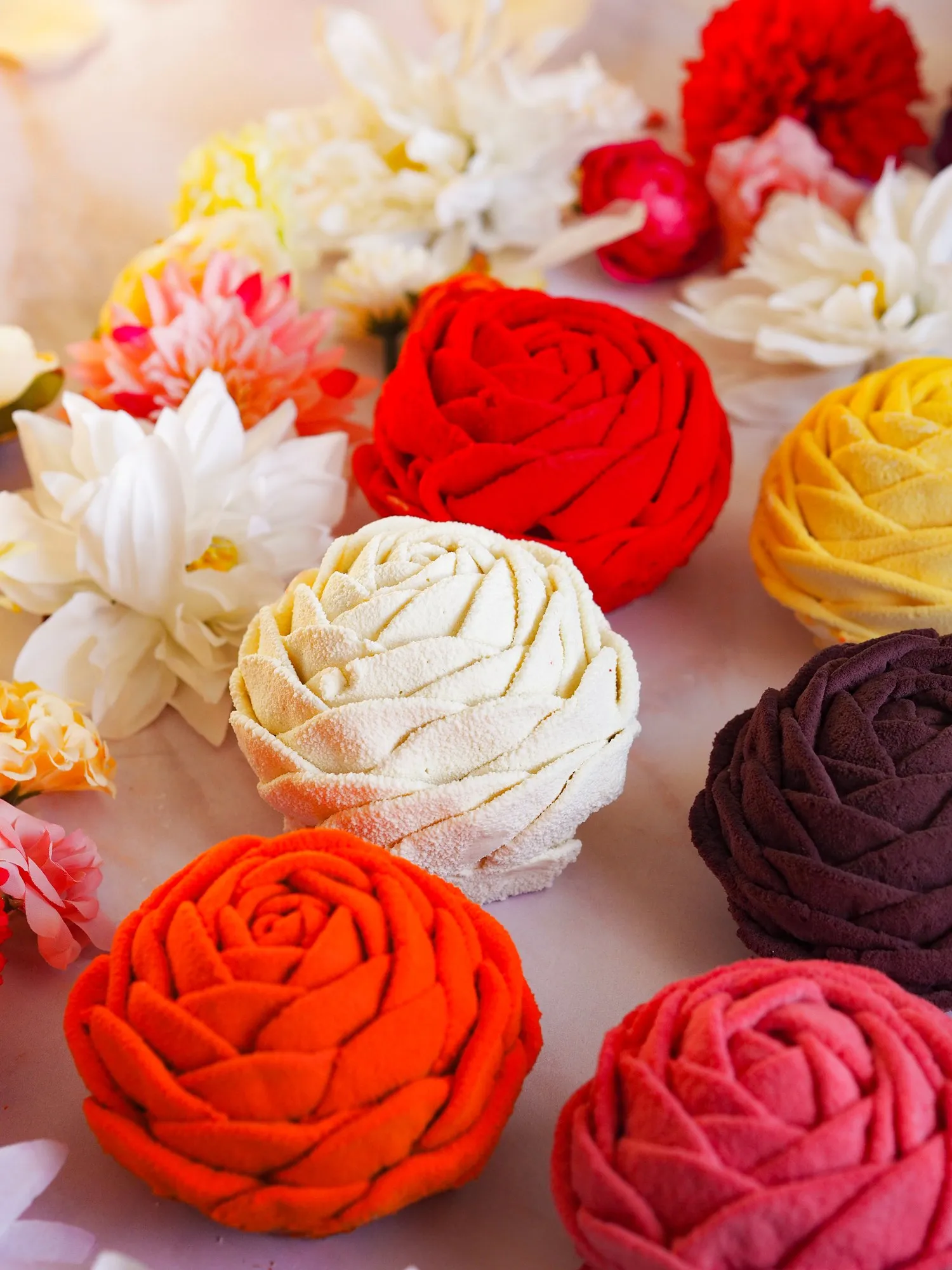 Roses BO&MIE veloutées, déclinées en plusieurs couleurs, posées parmi des fleurs