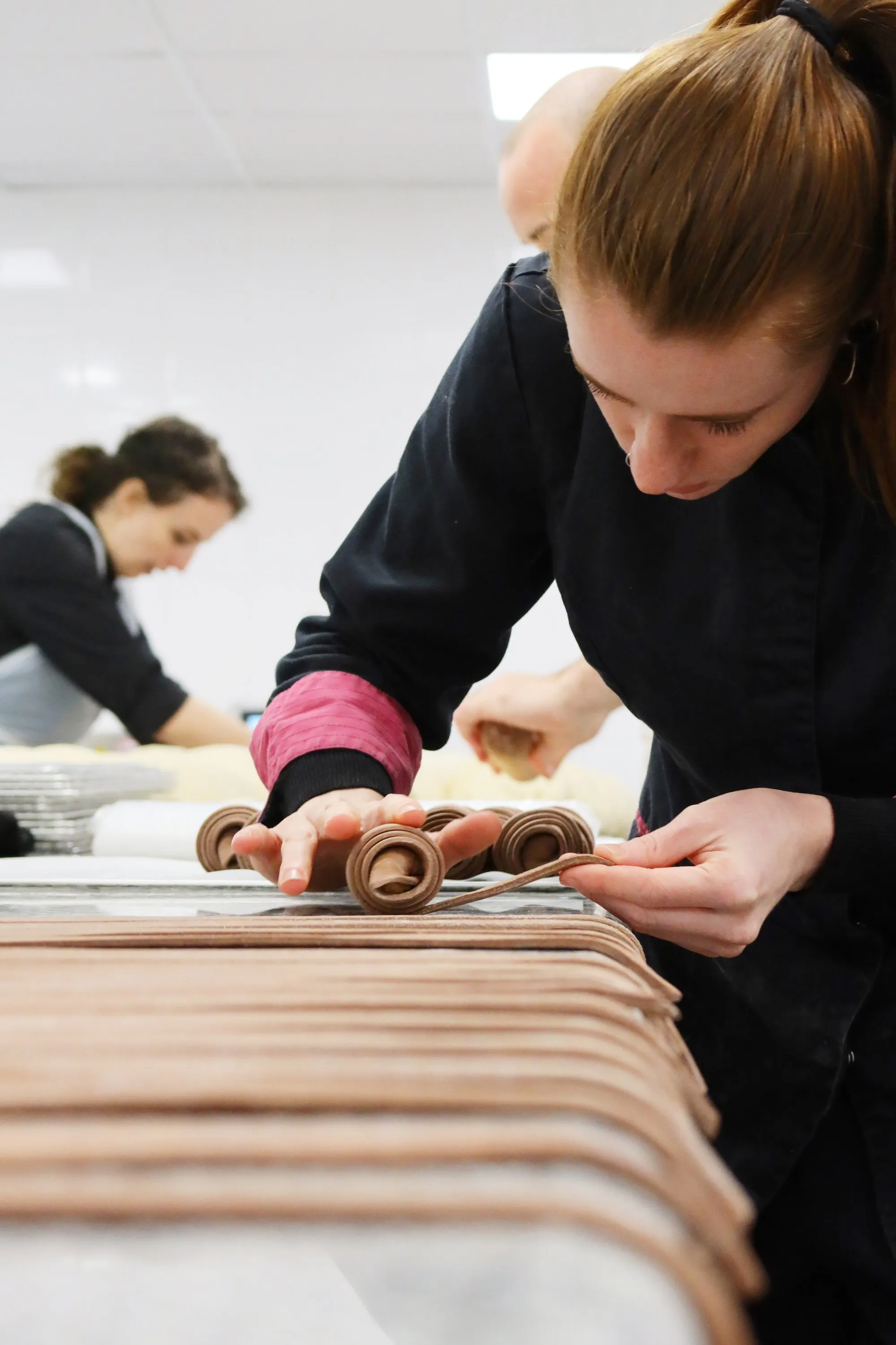 Le laboratoire BO&MIE : une pâtissière roule des bandes de pâte, une collègue travaille au poste voisin