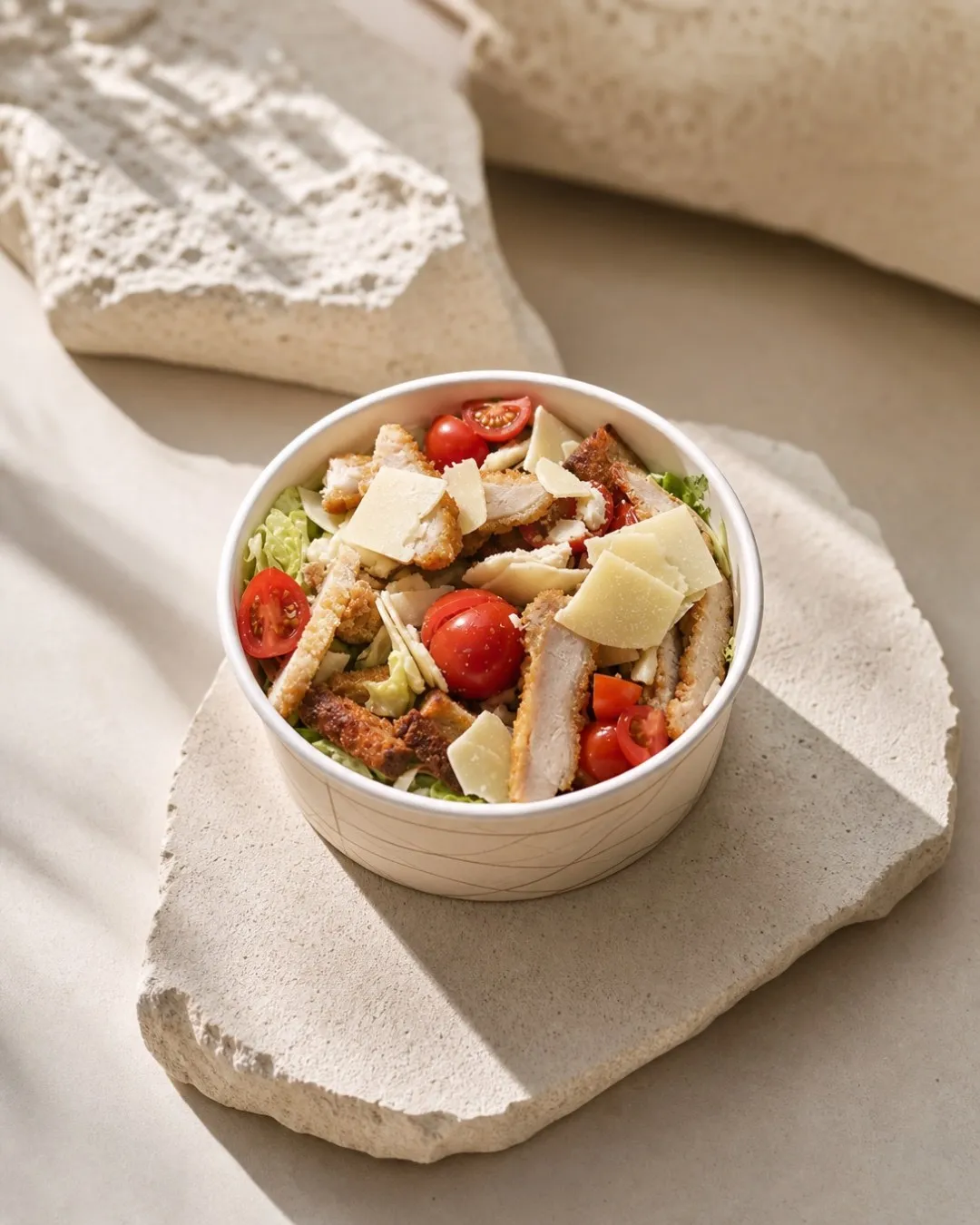 Une salade César BO&MIE dans son bol, poulet pané, copeaux de parmesan et tomates cerises